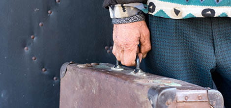 Elderly man carrying old beat up suitcase